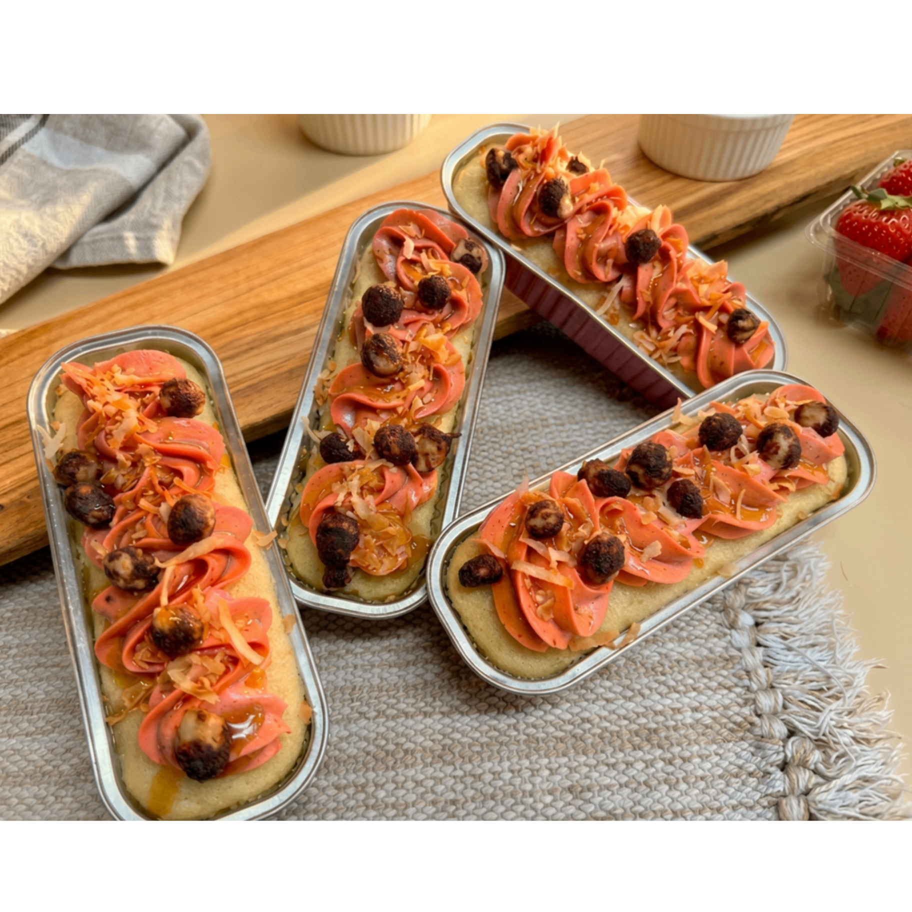Island Escape mini loaf cakes topped with tropical buttercream, toasted coconut, and chocolate-covered macadamia nuts
